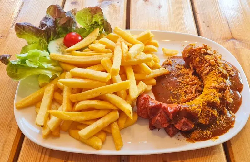 Currywurst mit Pommes und einem kleinen Salatbouquet