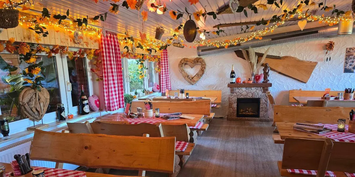 Herbstlich dekorierte Stube mit Lichterketten, Kaminofen und Holzbänken