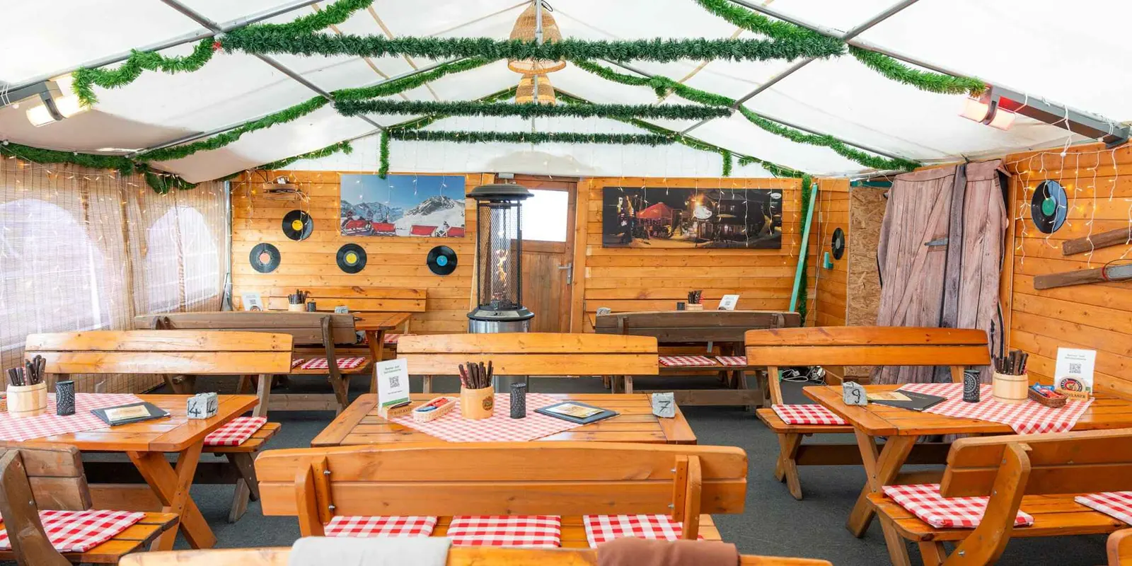 Beheiztes Zelt mit Holzwänden, Biertischgarnituren und Lichterketten für die kalte Jahreszeit